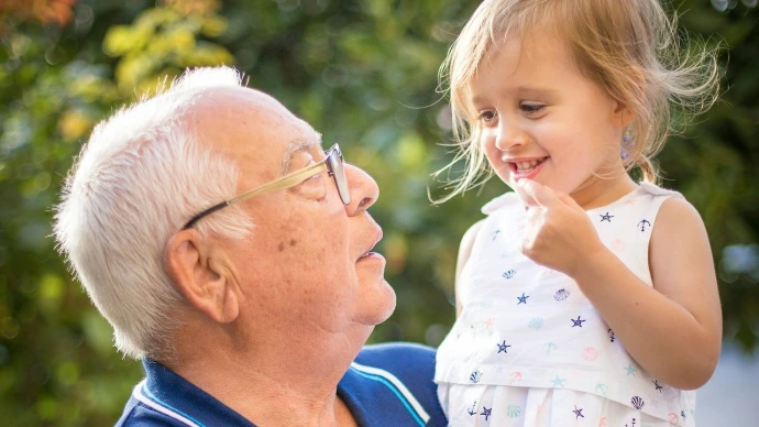 man in blue polo shirt carrying girl in white and pink floral dress