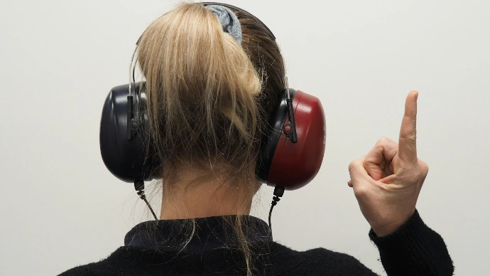 a woman wearing headphones pointing to the side